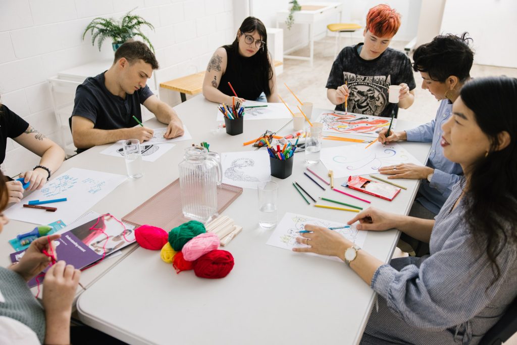 A group of people sitting around a table doing art and craft.